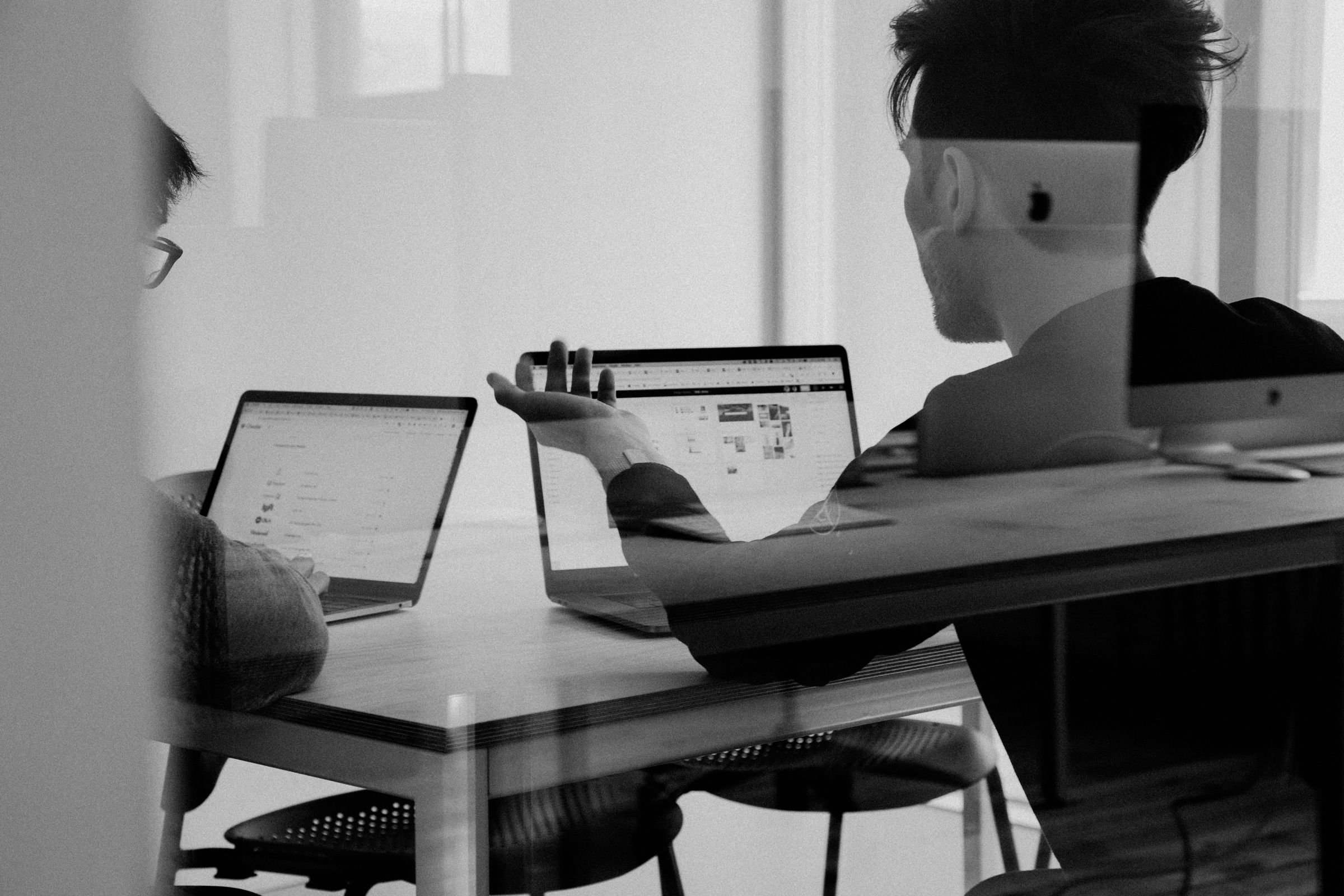 Black-and-white photo of a person working on a laptop at a desk