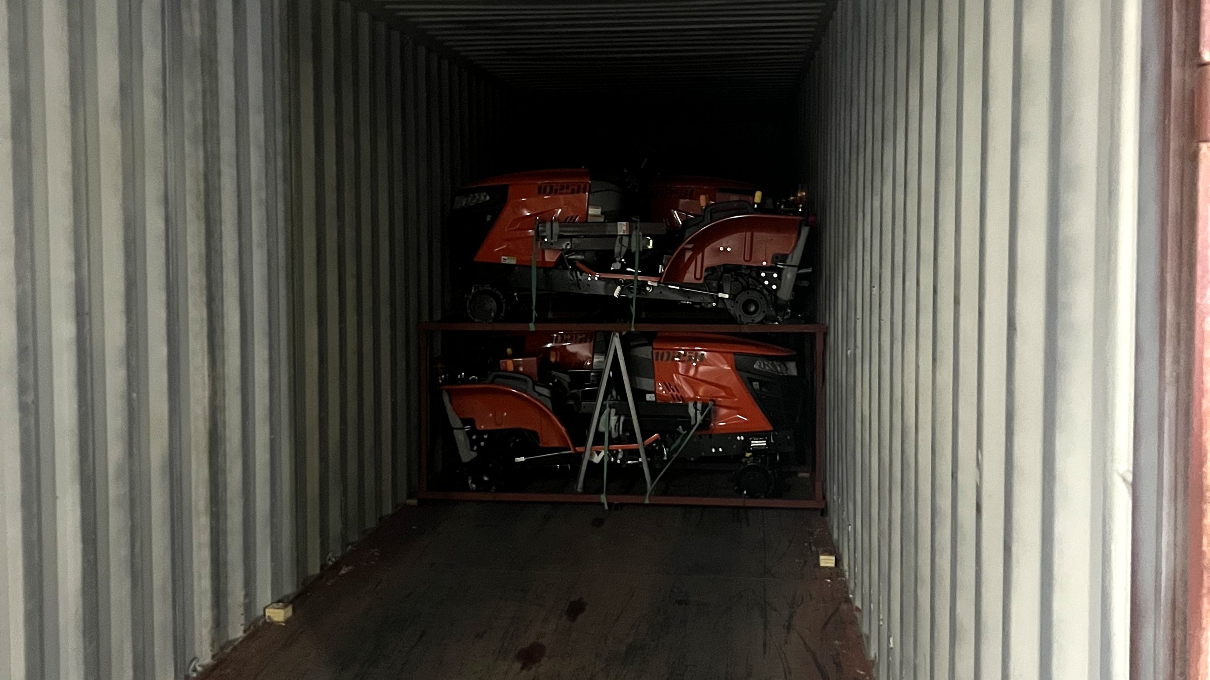 Compact tractors braced on racks at the back of a shipping container