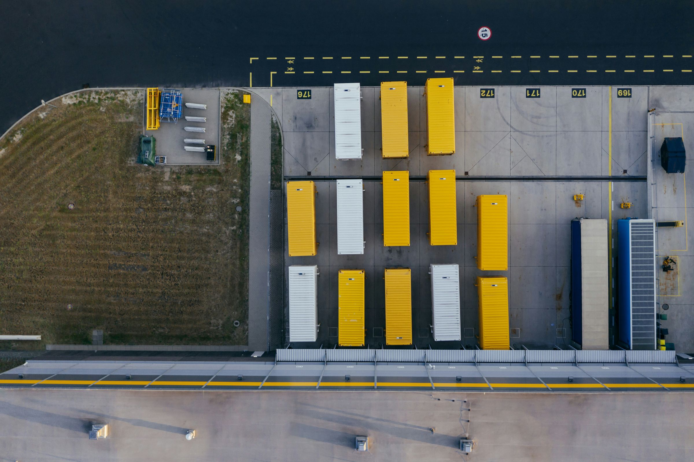 Aerial view of yellow and white shipping containers lined up on a quayside