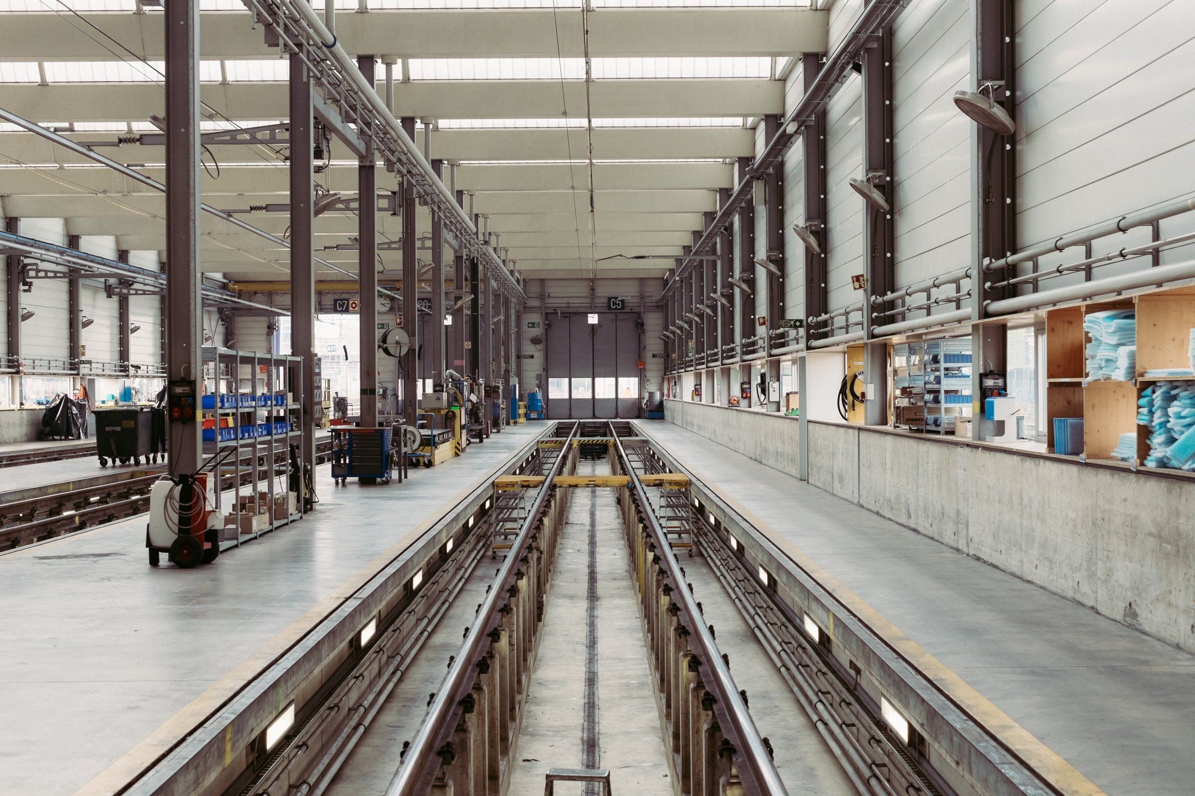 Inside a large, clean manufacturing hall with rails and workstations