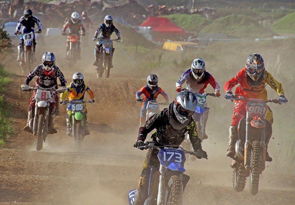 Motocross riders racing through dust on a dirt track
