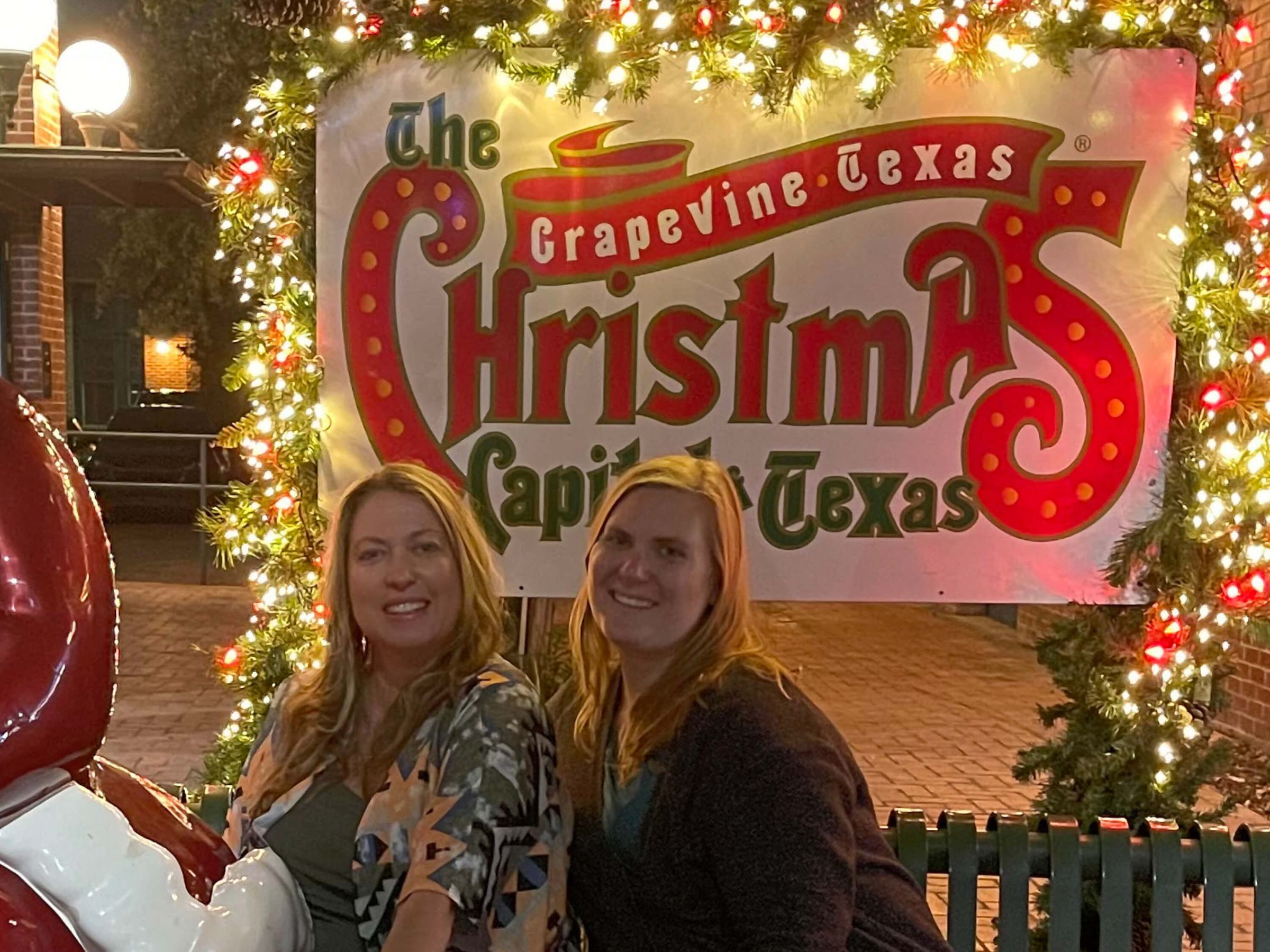Katie Armenta and Monica Caressimo in front of a Christmas sign in Grapevine, Texas