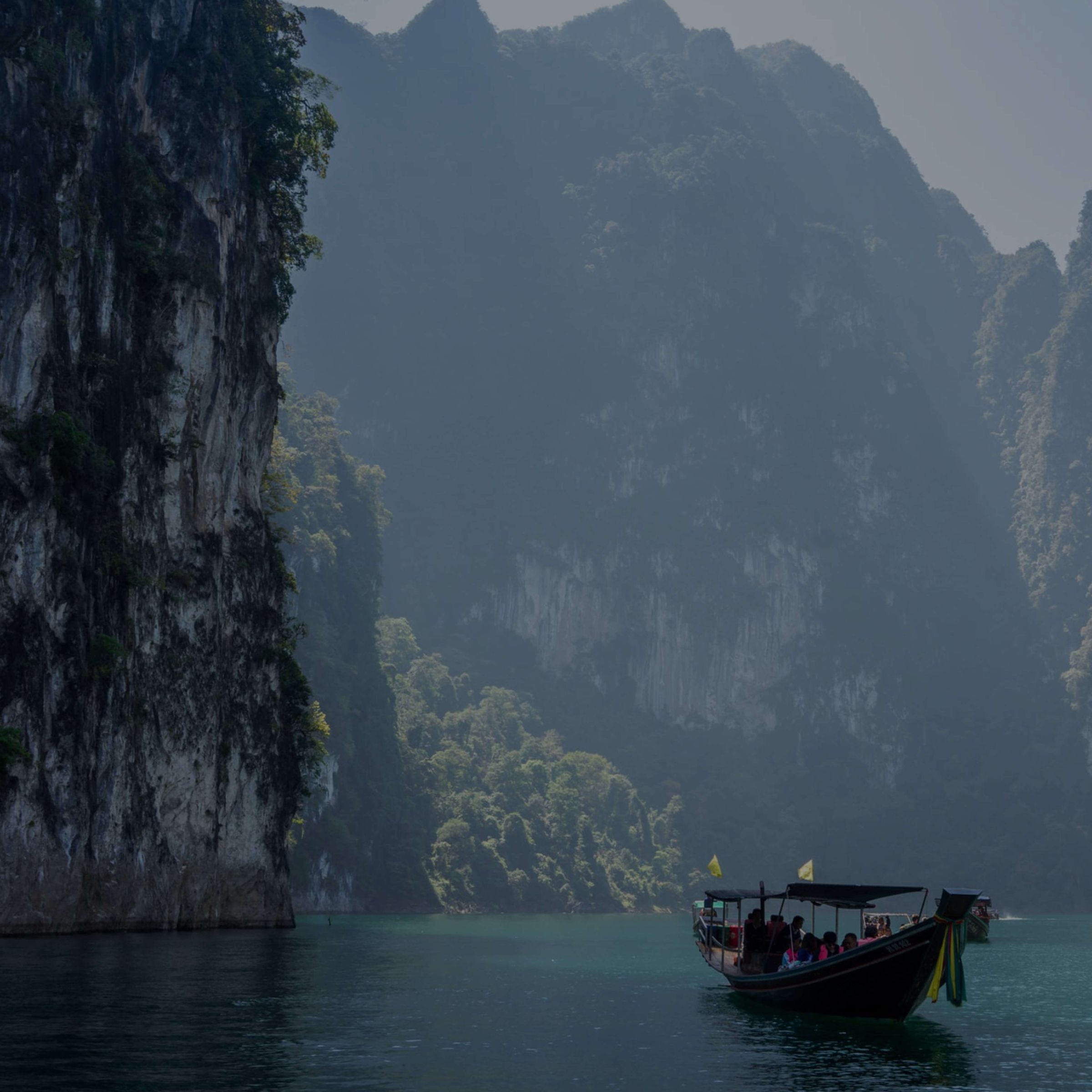 A longtail boat beneath steep limestone cliffs in Thailand