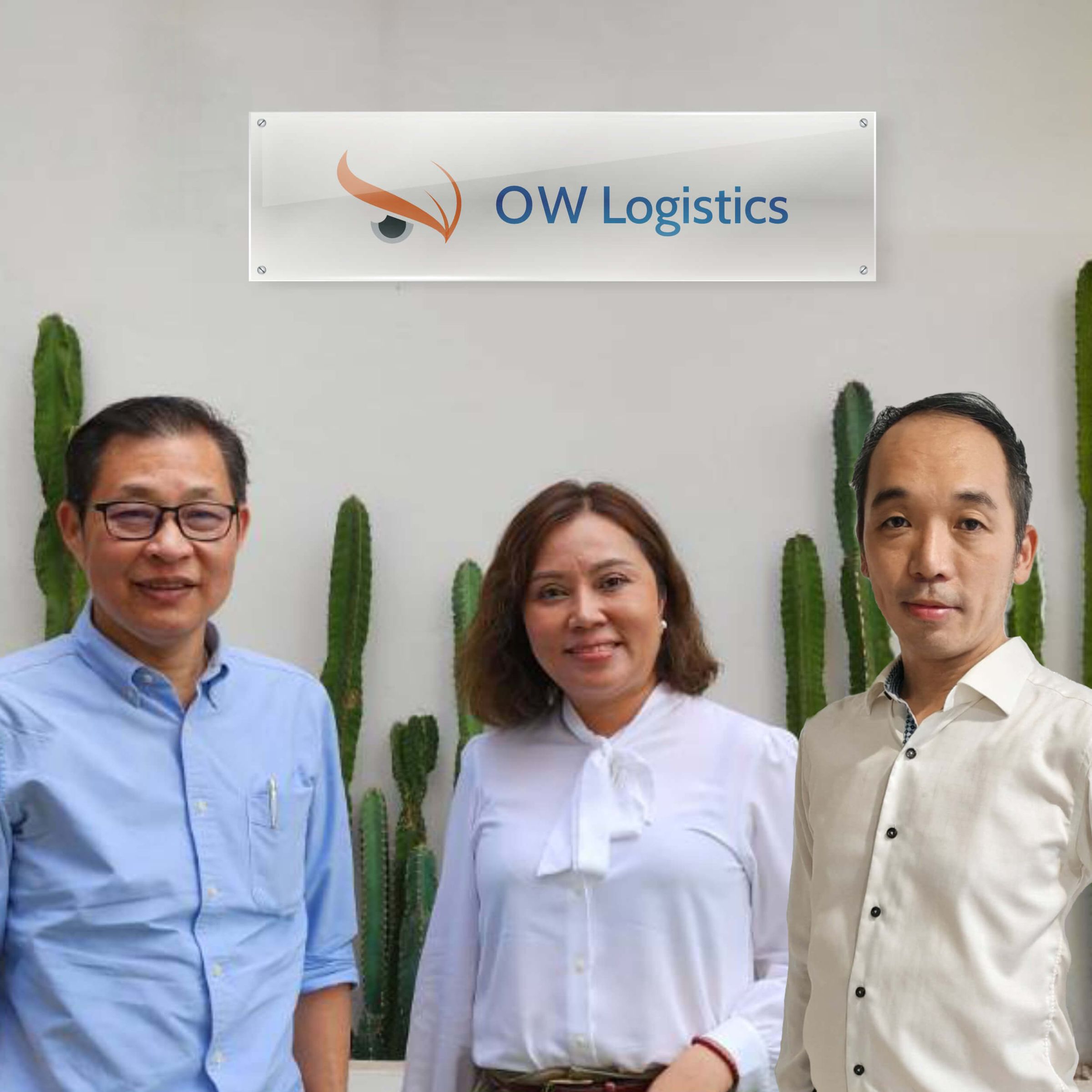 Three members of the OWL Laos team in front of the OW Logistics sign