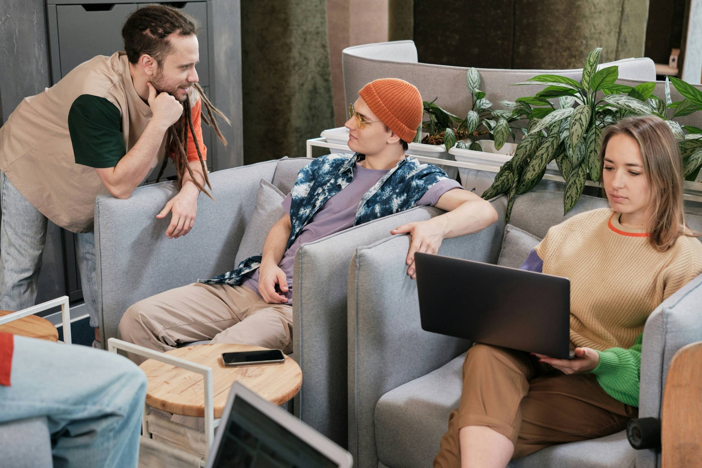 Colleagues relaxing on a sofa with a laptop in a casual office space