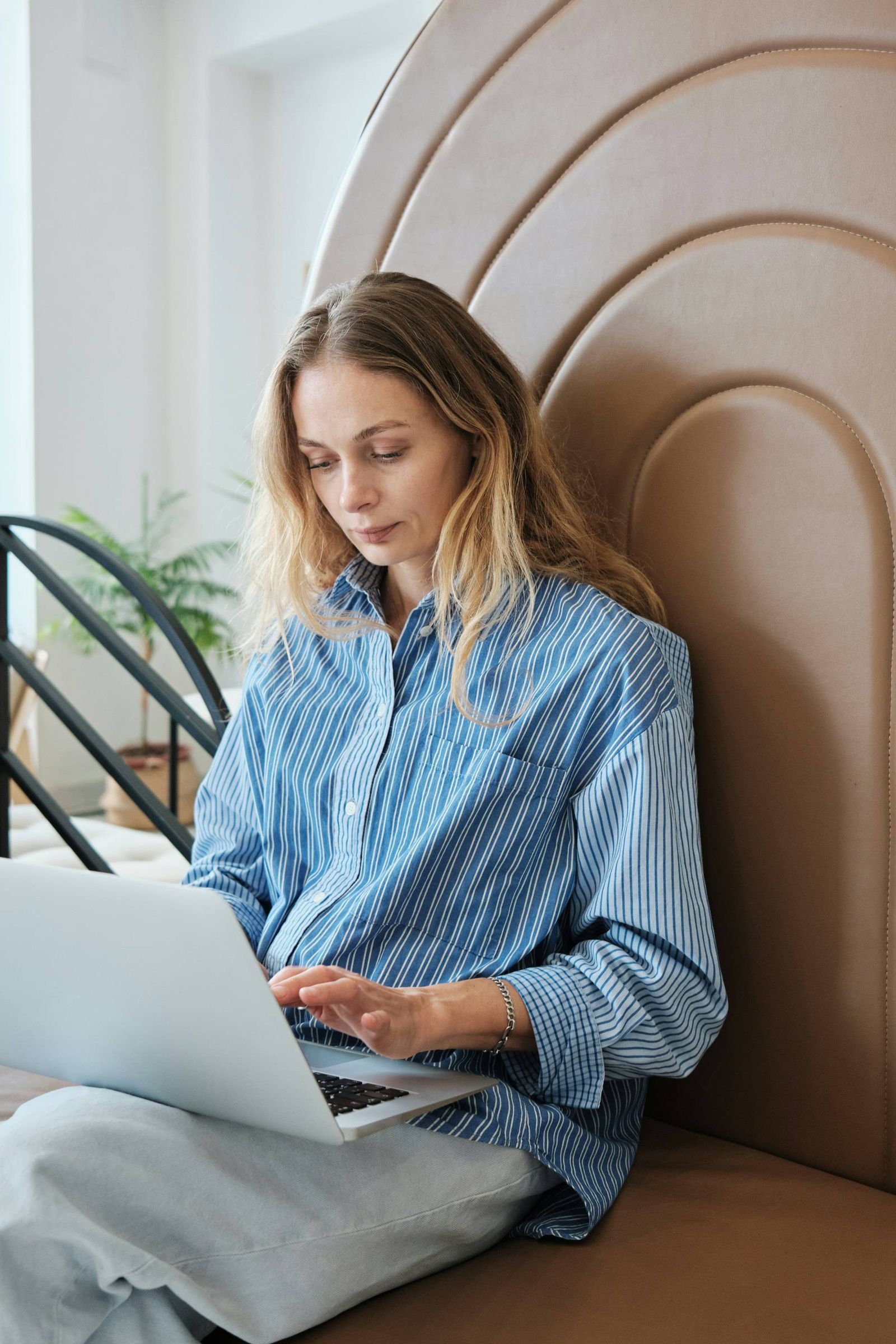 A woman sitting cross-legged on a bench, working on a laptop